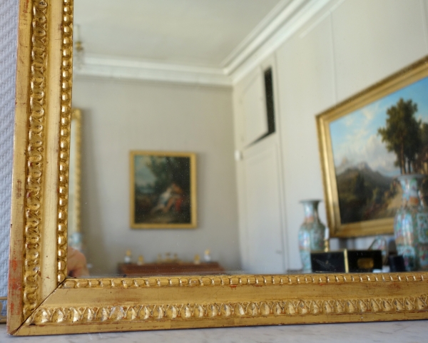 Grand miroir en bois doré d'époque Louis XVI, modèle Provençal avec fronton à trophée de musique